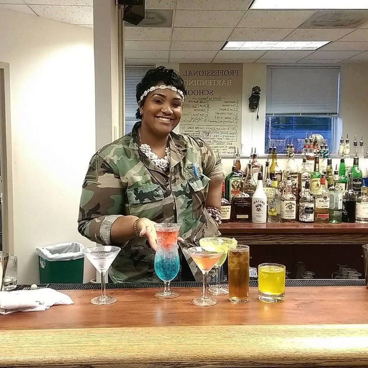 Student presenting colorful cocktails behind the training bar